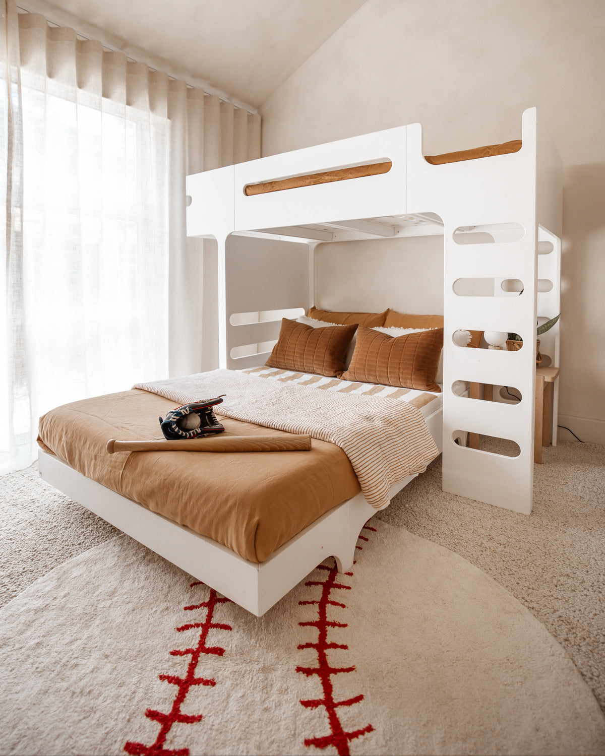 White bunk bed with brown bedding in a room with light-colored walls and a rug.