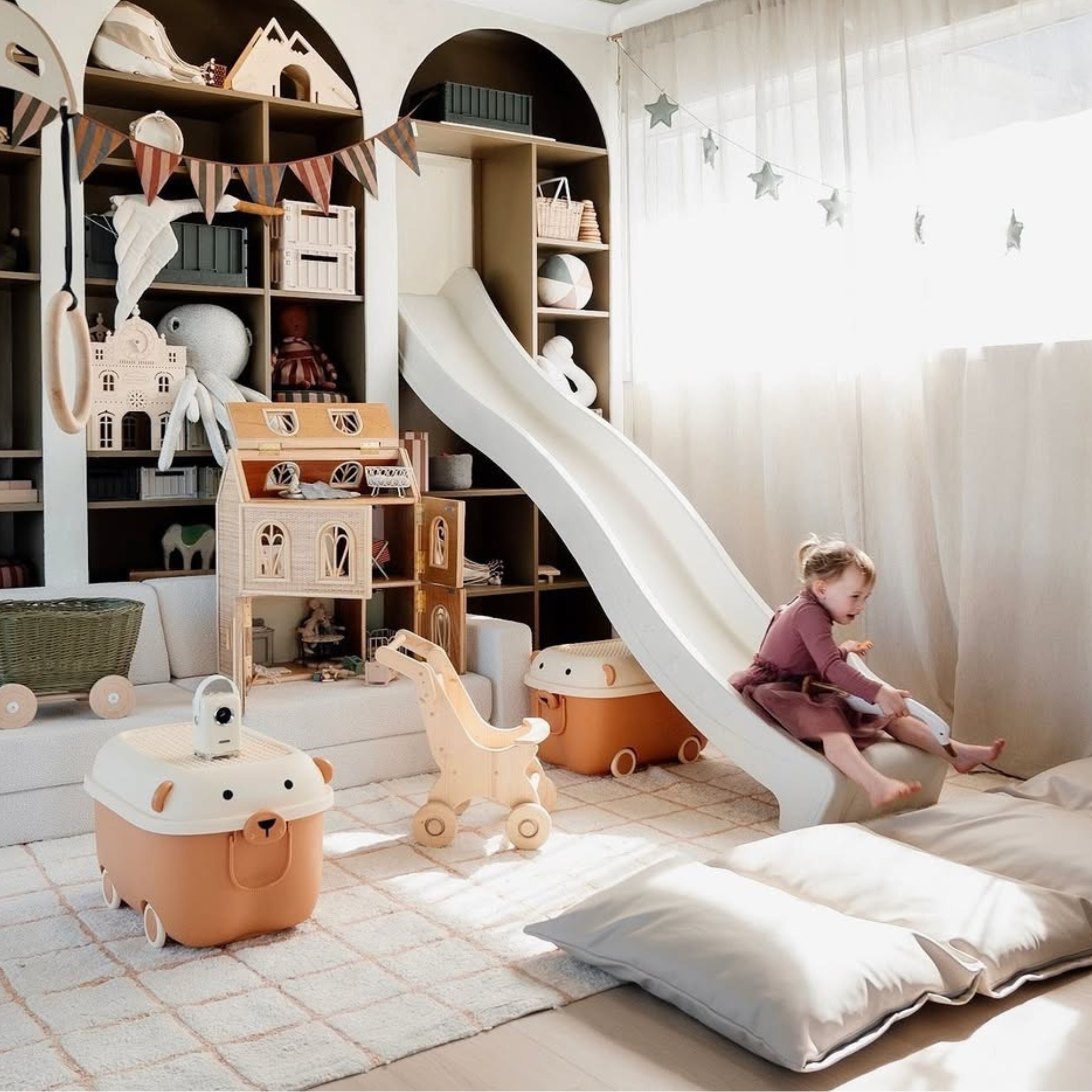 Children's playroom with toys, a slide, and a child sitting on a cushion.