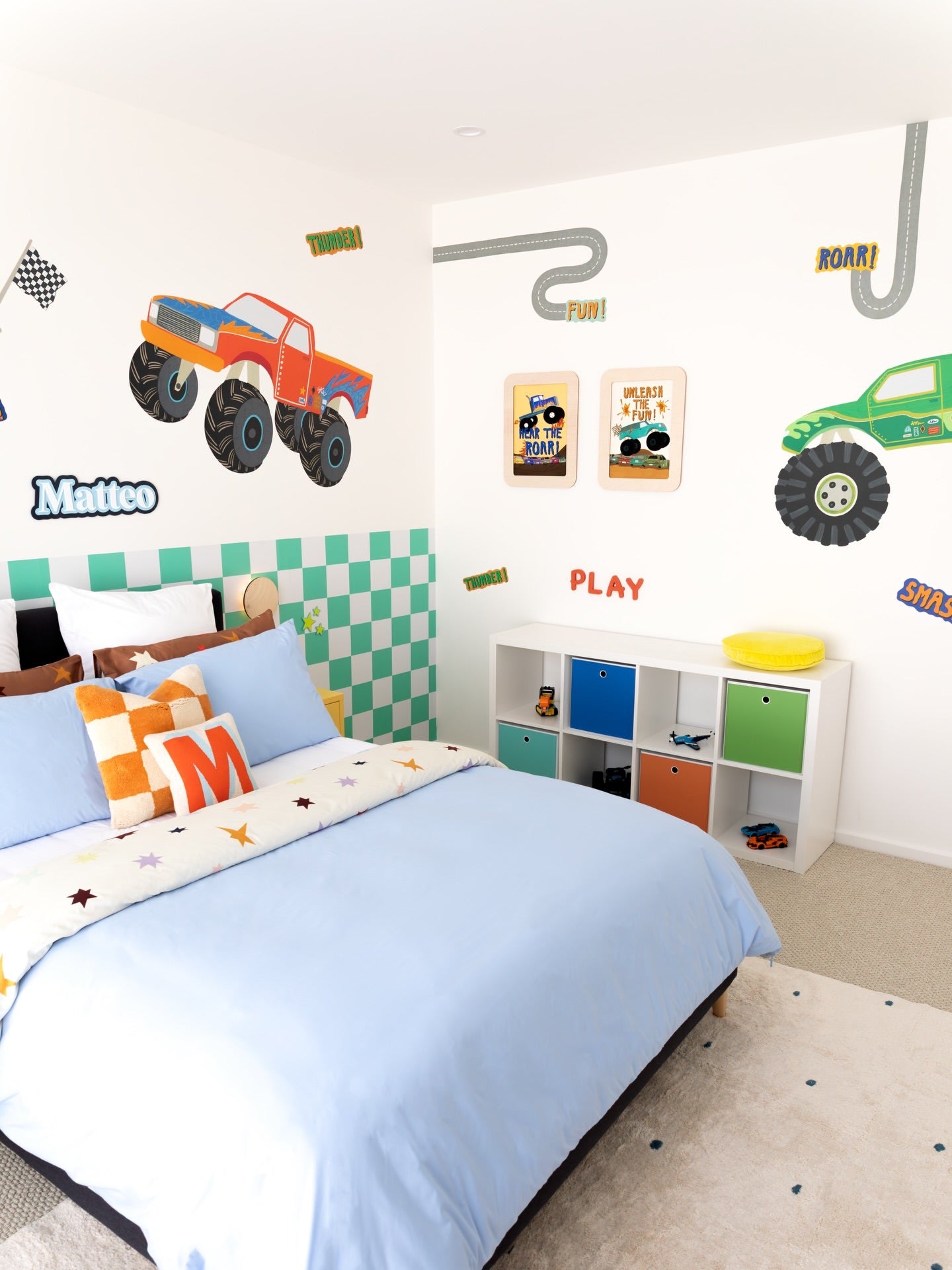 Children's bedroom with monster truck decals and colorful furniture.