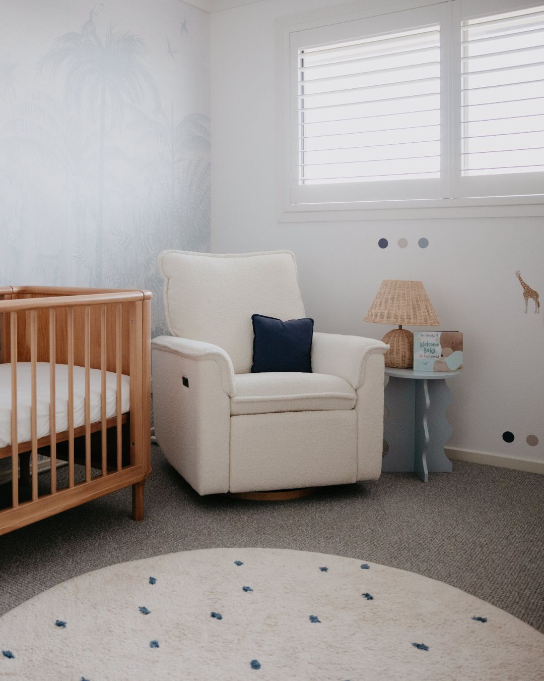 Nursery room with a crib, armchair, and round dot round rug.
