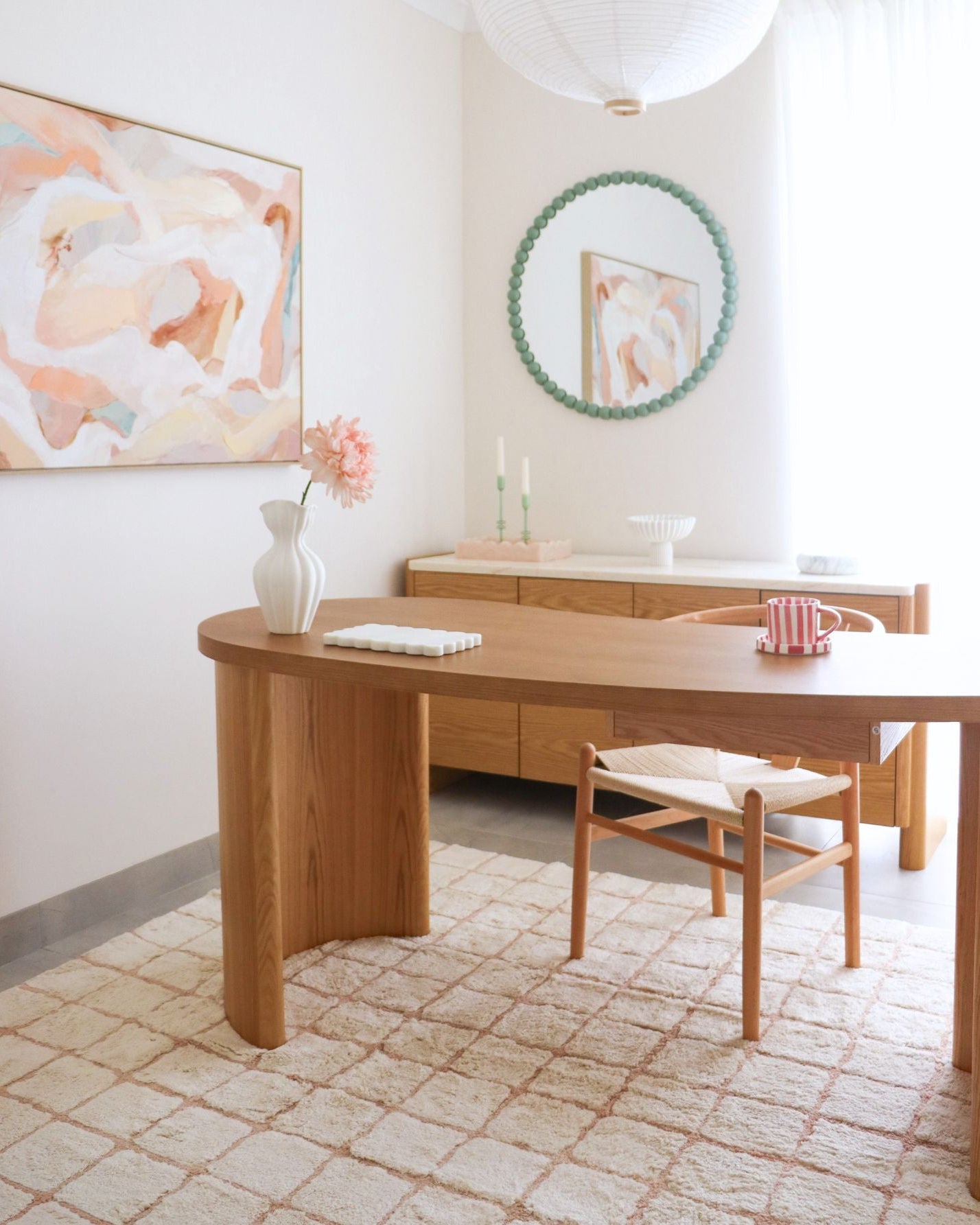 Modern interior with wooden desk, chair, and abstract art on wall.